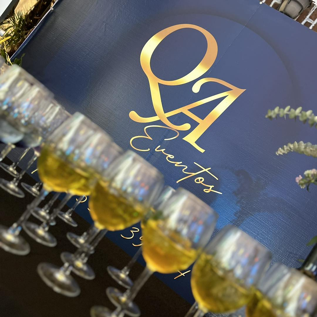 Copa de champagne frente al logo QA Eventos